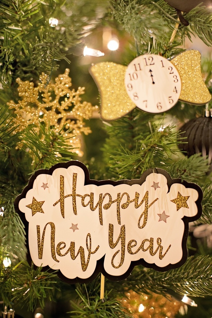 happy new year sign and clock showing midnight on an evergreen tree